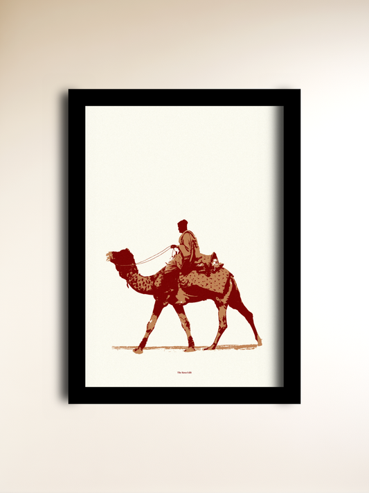 A framed art print featuring a sepia-toned illustration of a camel with a rider in Rajasthan, displayed against a light beige wall.