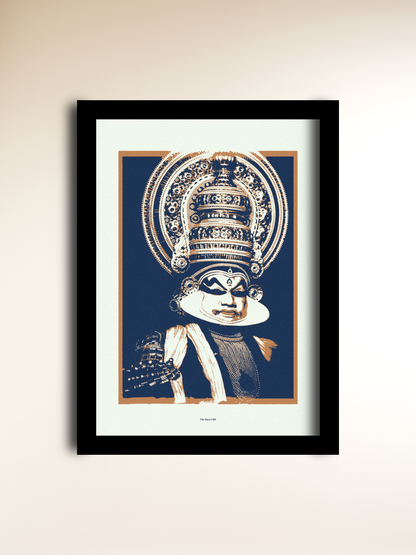 A framed art print featuring a stylized illustration of Kathakali, shown against a dark blue background with cream and tan details. The print is mounted with a wide cream mat and enclosed in a slim black frame, hanging on a light beige wall.