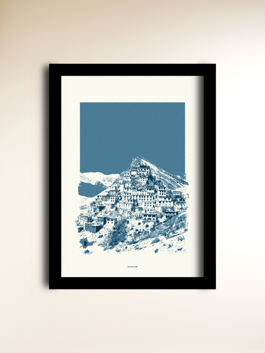 A framed art print featuring a stylized blue and white illustration of Spiti Valley, displayed on a warm beige wall.