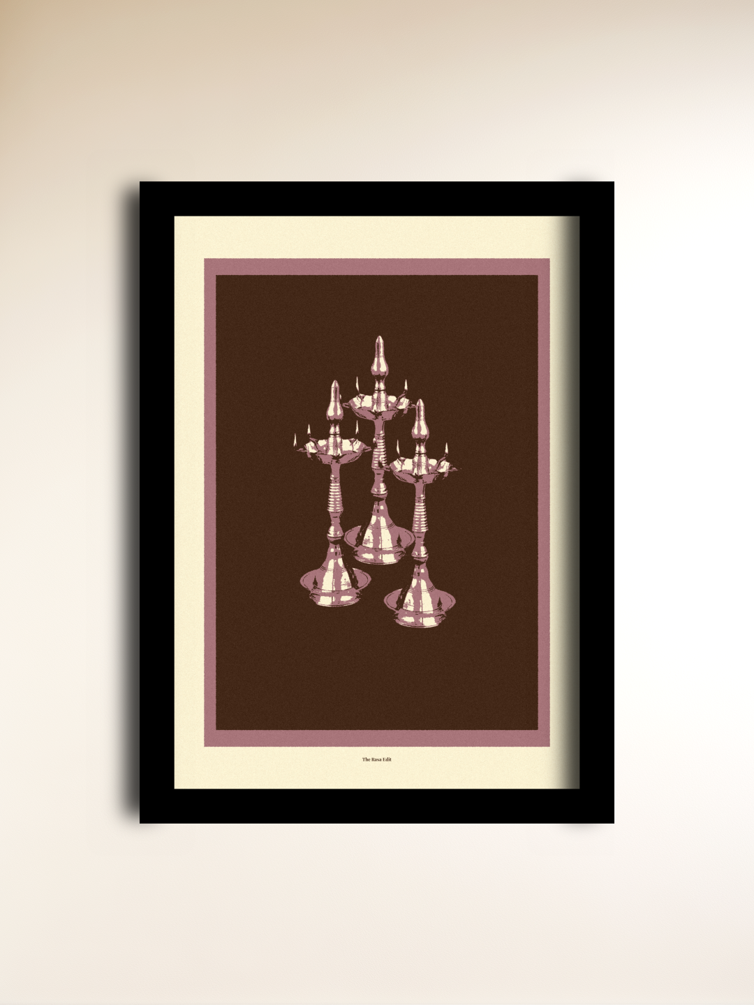 Framed wall art featuring an illustration of three Nilavilakku on a dark brown background with a mauve border, mounted on a light beige wall.